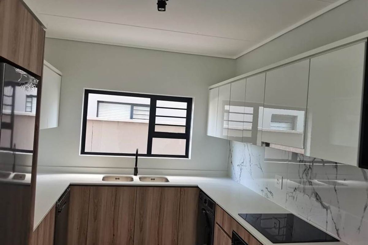 Modern kitchen featuring sleek white and wood-grain cabinetry, stone countertops, marble-look splashback, and integrated appliances including a hob and oven.