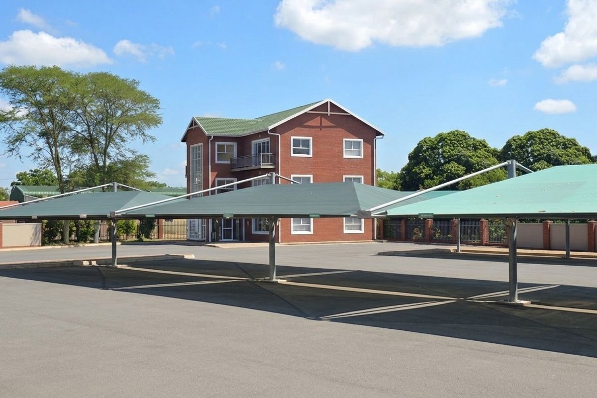 Exterior view of a multi-story brick office building featuring a paved parking area with covered shade cloth carports.