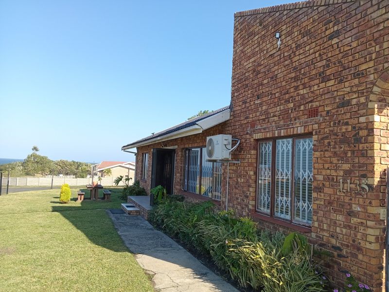 A view of the rear exterior of a face brick house featuring a concrete walkway, lawn, and an installed air conditioning unit.