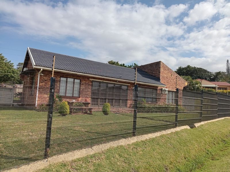 A well-maintained face brick house featuring a tiled roof, secure perimeter fencing with electric wires, and security gates over windows and doors.