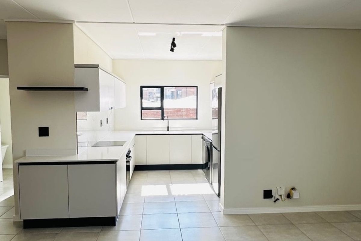 A modern, clean-lined kitchen featuring white cabinetry, stone countertops, and neutral ceramic floor tiles, offering a bright and functional workspace.