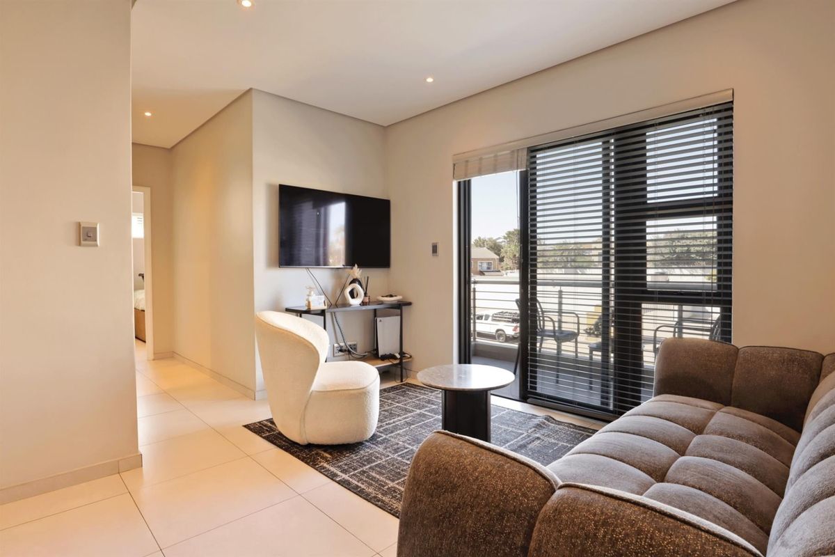 Modern living room featuring tiled flooring, recessed downlights, and a sliding glass door providing access to a balcony.