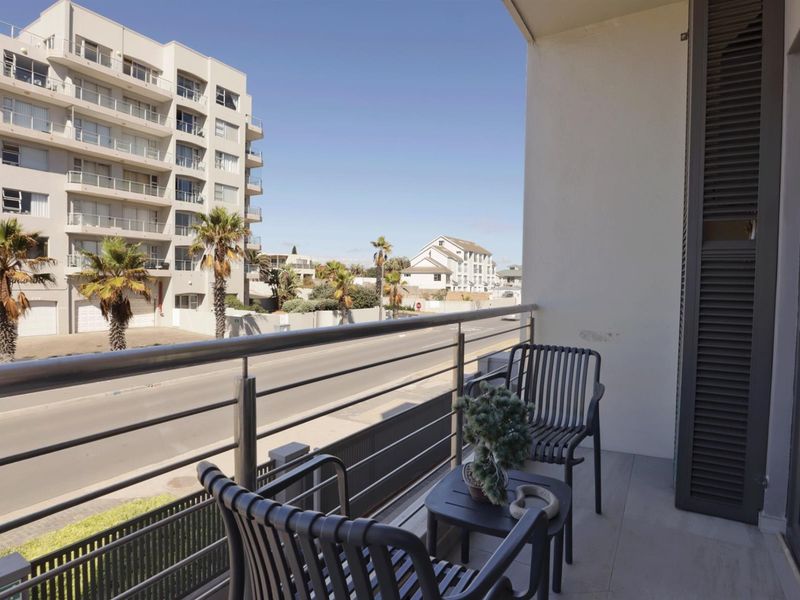 A private balcony featuring tiled flooring and a stainless steel balustrade, offering an open view of the surrounding street and neighborhood.