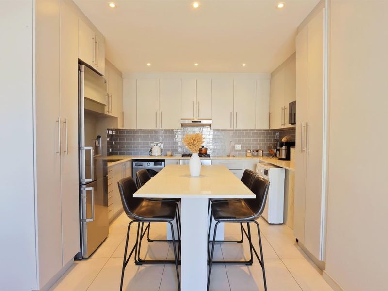 Modern kitchen featuring sleek built-in cabinetry, subway tile backsplash, stone countertops, and integrated appliances with recessed lighting throughout.