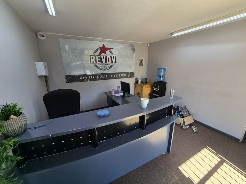 A functional office reception area featuring a built-in desk, fluorescent lighting, and wall-mounted security infrastructure.