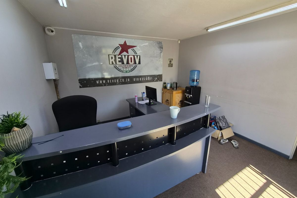 A functional office reception area featuring a built-in desk, fluorescent lighting, and wall-mounted security infrastructure.