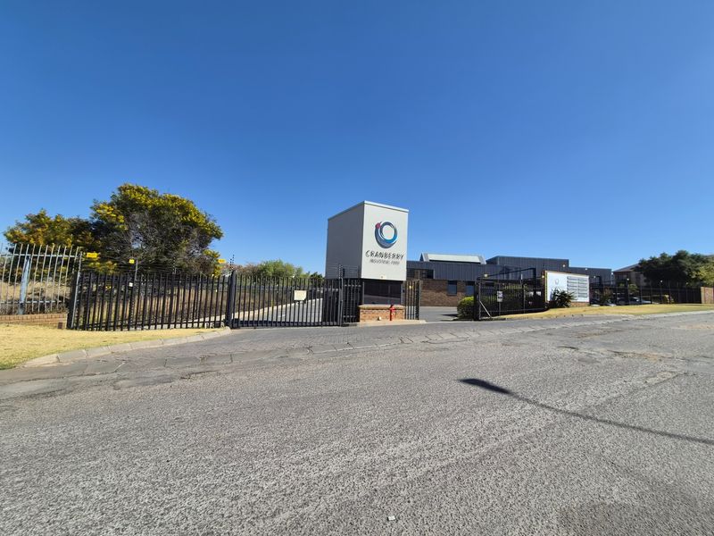 Front entrance view of Cranberry Industrial Park featuring secure gated access, perimeter electric fencing, and prominent signage pylon.