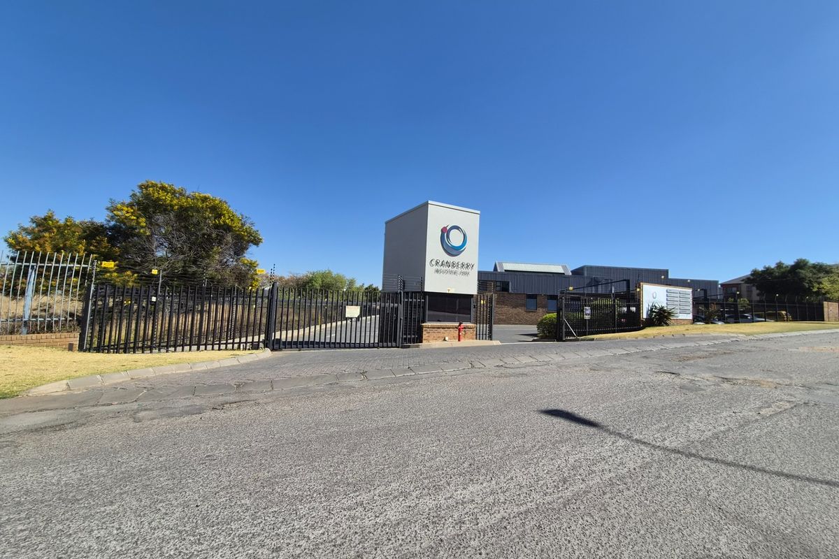 Front entrance view of Cranberry Industrial Park featuring secure gated access, perimeter electric fencing, and prominent signage pylon.