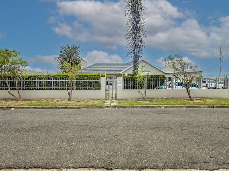 Front exterior view of the office property featuring a secure perimeter wall, metal fencing, pedestrian gate, and a tiled roof structure.