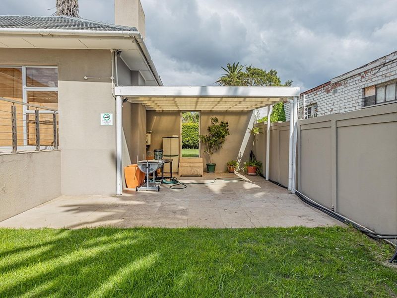 A covered outdoor patio area featuring tiled flooring, adjacent to the main building structure with access via a sliding door.