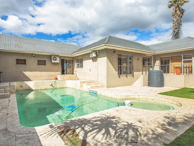 Outdoor pool area featuring a tiled patio, swimming pool, and exterior building access with mounted air conditioning units.