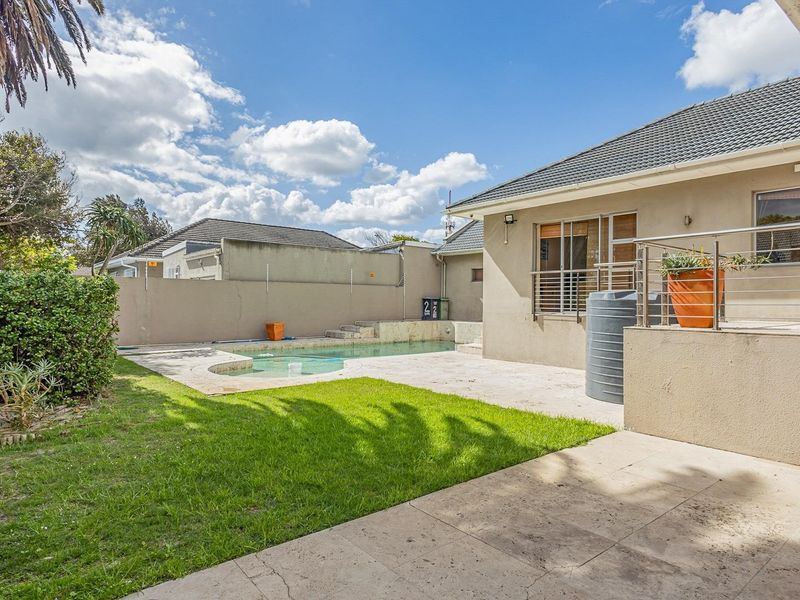 Outdoor pool area featuring a paved patio, swimming pool, perimeter wall with electric fencing, and an integrated water tank.