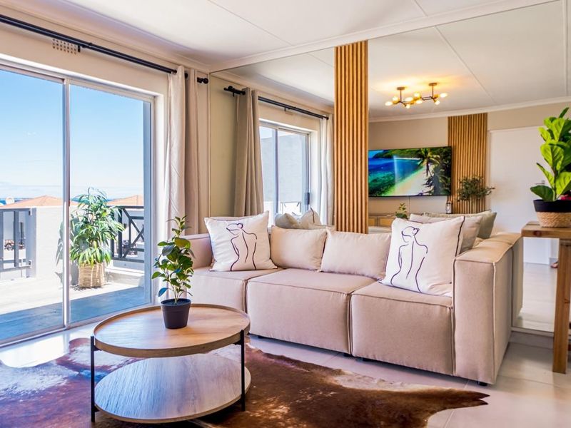 A bright living room featuring a large sliding glass door leading to a balcony, a mirrored wall, and decorative slatted wood paneling.