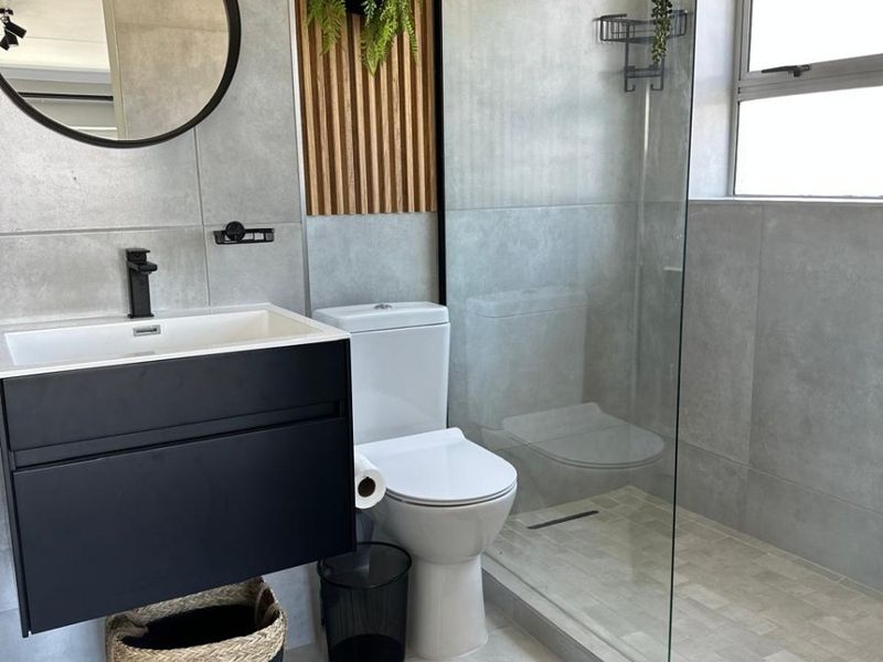 Modern bathroom featuring a wall-mounted vanity, walk-in shower with glass screen, rain shower head, and stylish timber slat wall detailing.
