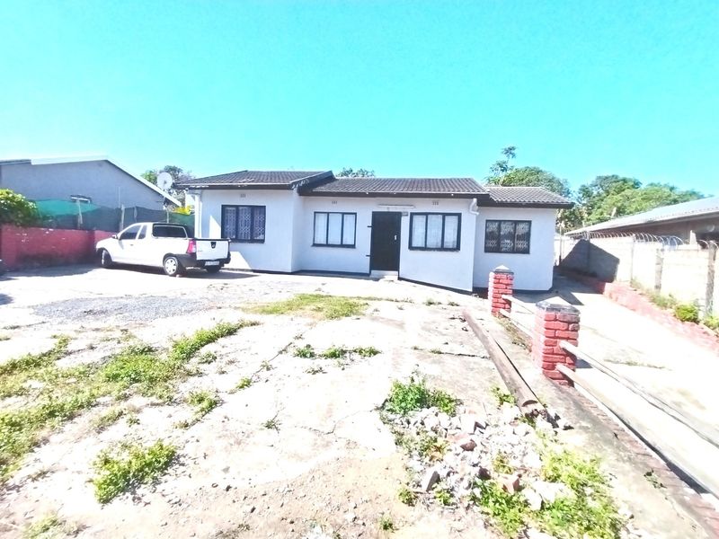 Front view of a single-story house featuring a tiled roof, security bars on windows, and a concrete driveway with boundary walling.