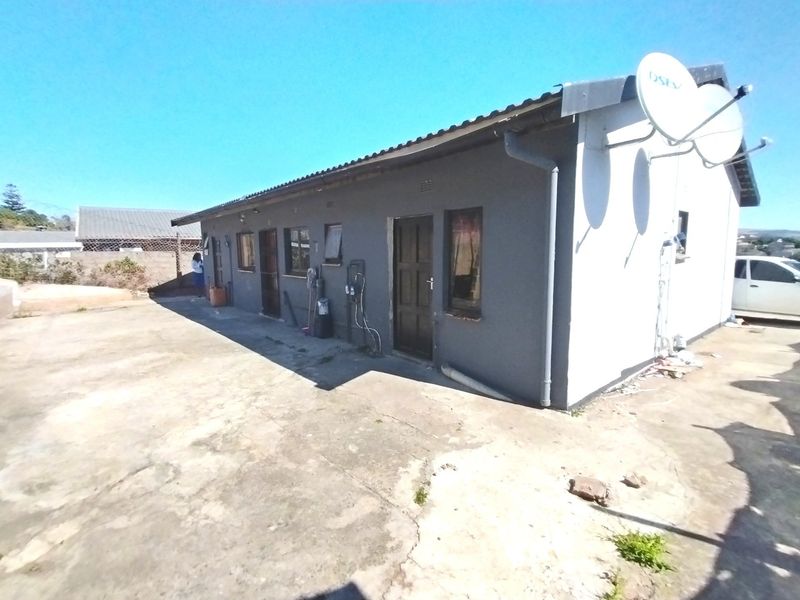 Rear exterior view of the house featuring a concrete paved area, satellite dish installation, and standard building facade with guttering and downpipes.