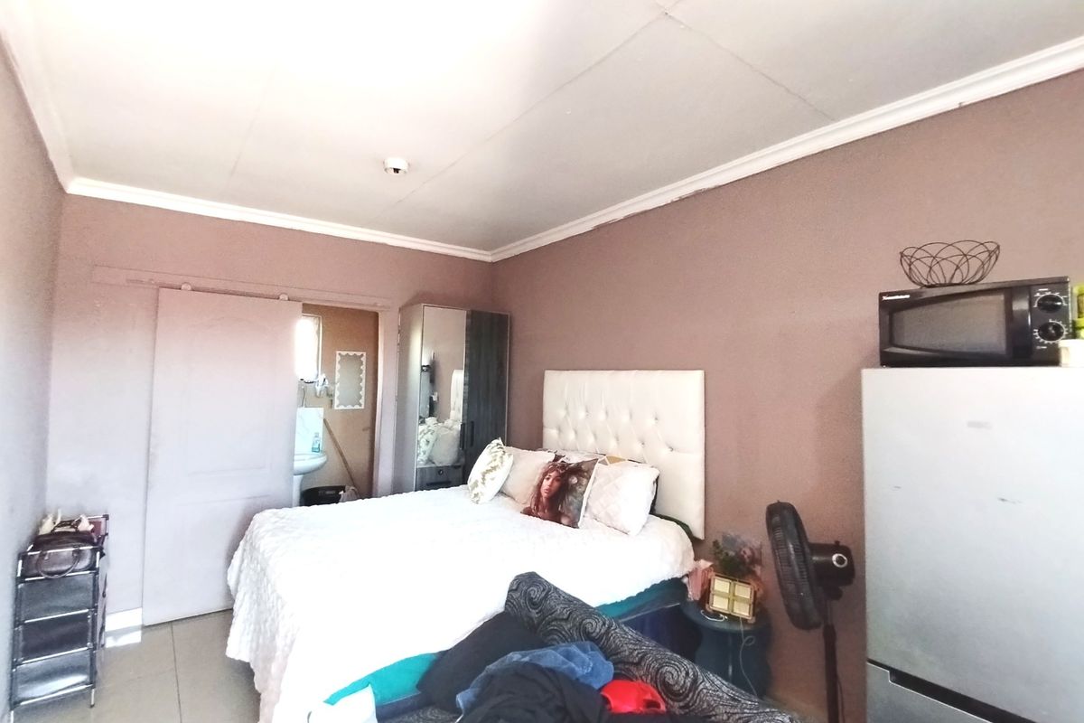 A bedroom featuring tiled flooring, ceiling cornicing, and a sliding door leading to an adjacent bathroom area.