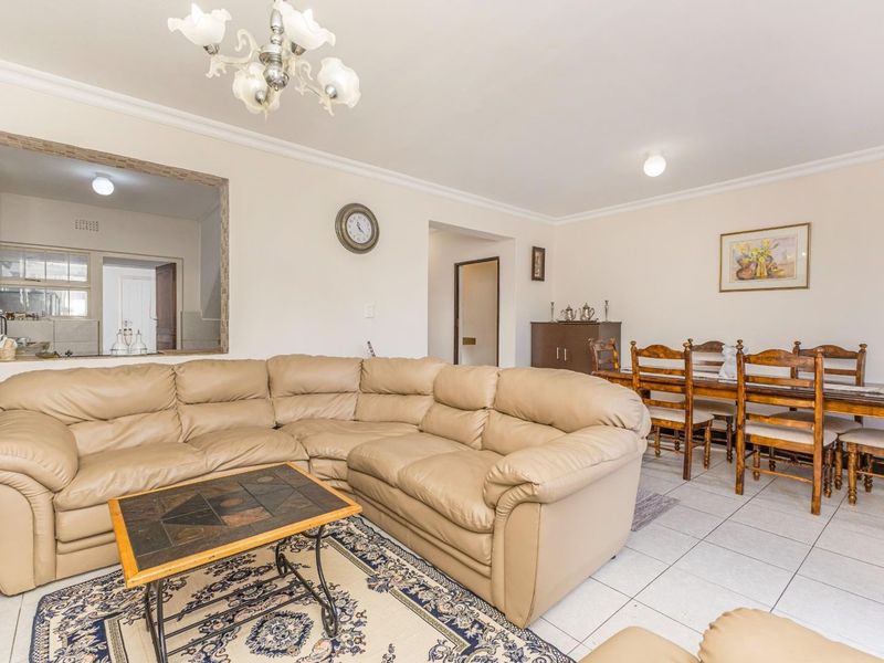 Open-plan living and dining area featuring ceramic floor tiles, coved cornicing, and a convenient pass-through window connecting to the kitchen.