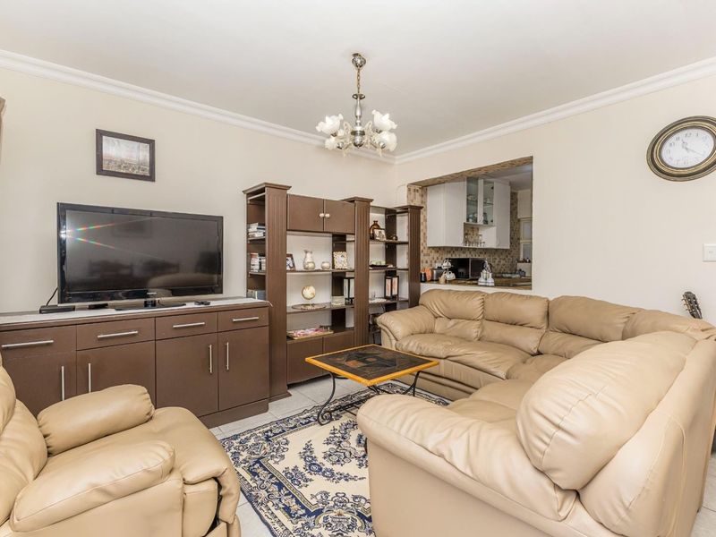 Open plan living area featuring tiled flooring, decorative ceiling cornice, and a convenient pass-through window connecting to the kitchen space.