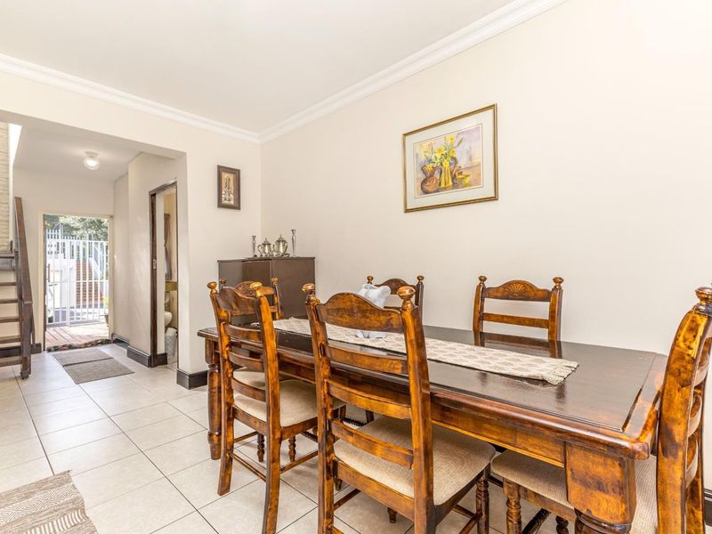 Dining area featuring tiled flooring and crown molding, with an adjacent staircase leading to the entrance.