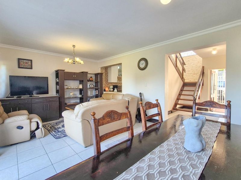 Open-plan living and dining area featuring tiled flooring, neutral walls, and a staircase leading to the upper level.