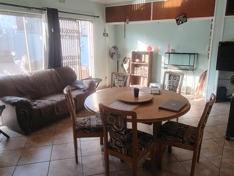 A living and dining area featuring tiled flooring, built-in overhead storage cabinets, and a sliding glass door providing access to the exterior.