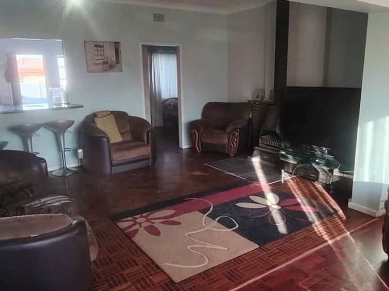 Spacious living room featuring classic parquet flooring, a built-in fireplace, and a convenient serving hatch connecting to the kitchen area.