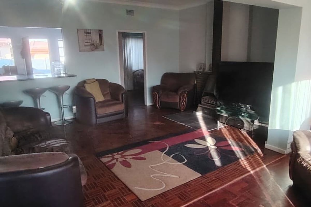 Spacious living room featuring classic parquet flooring, a built-in fireplace, and a convenient serving hatch connecting to the kitchen area.