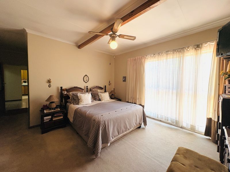 Spacious bedroom featuring a ceiling fan, exposed timber beam, and large sliding glass doors providing natural light.