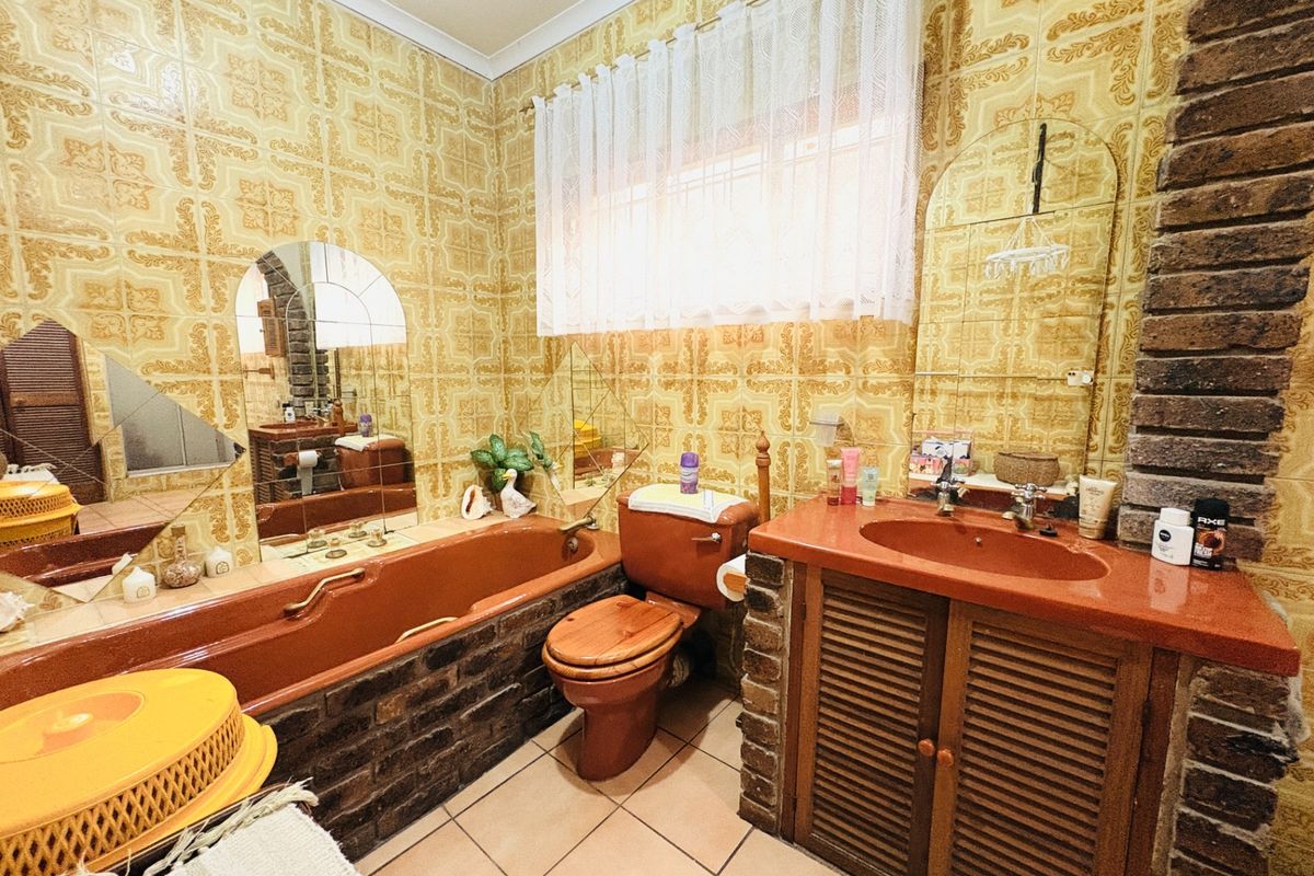 A dated bathroom featuring original terracotta-colored sanitaryware, brickwork accents, and patterned wall tiles, offering significant potential for a modern renovation.