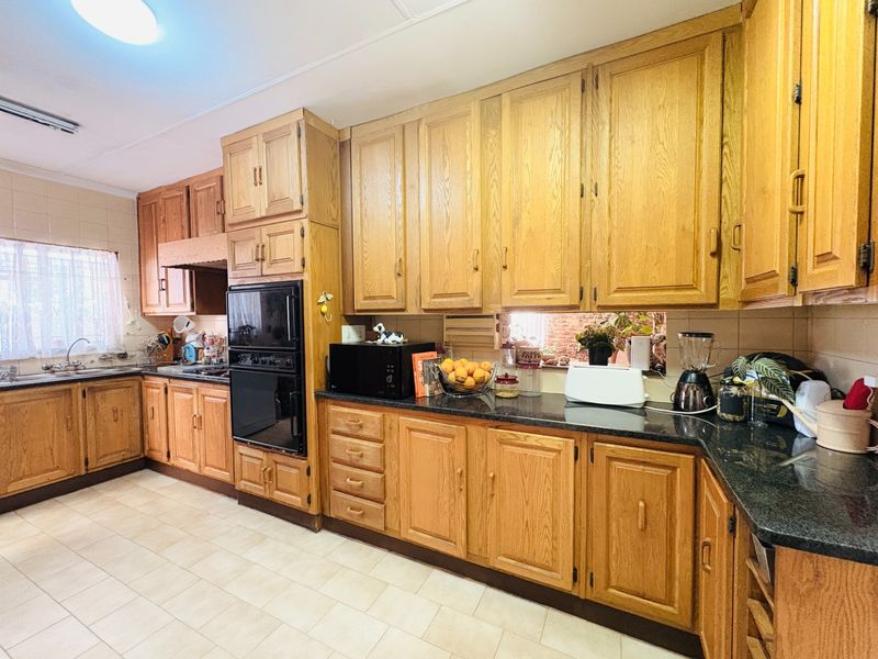 A functional kitchen featuring traditional oak cabinetry, granite countertops, built-in double oven, and ceramic tile flooring, offering a classic and durable workspace.