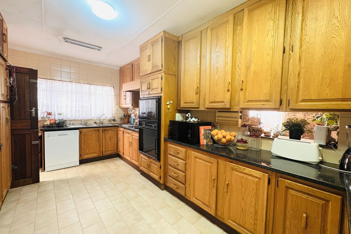 A functional kitchen featuring traditional oak cabinetry, dark granite countertops, tiled flooring, and a built-in double oven, offering a classic aesthetic.