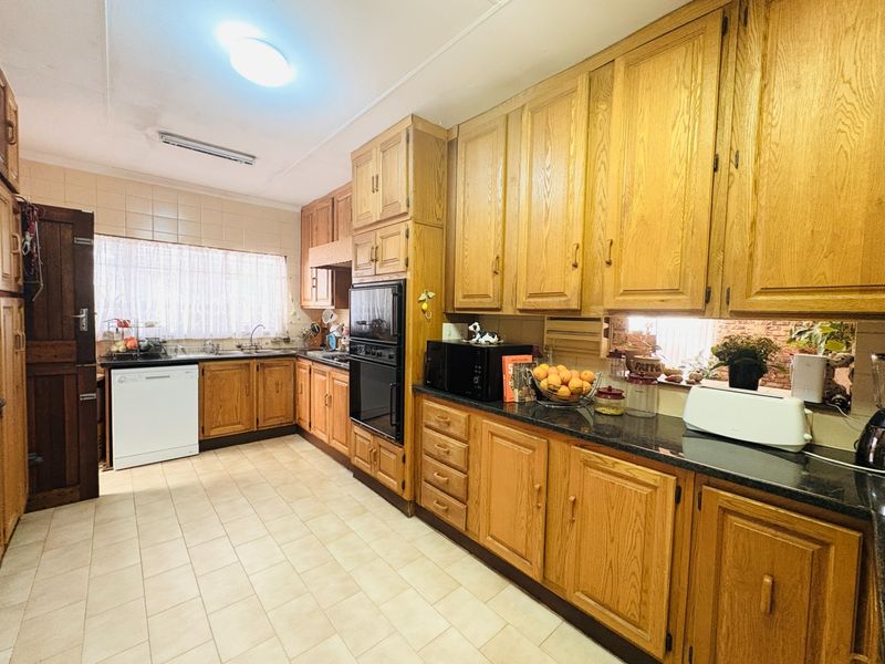A functional kitchen featuring traditional oak cabinetry, dark granite countertops, tiled flooring, and a built-in double oven, offering a classic aesthetic.