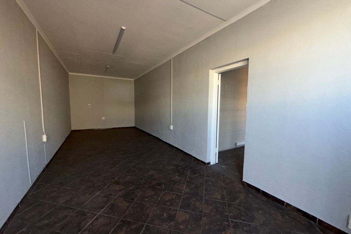 An empty, functional office space featuring tiled flooring, neutral walls, and overhead fluorescent lighting, suitable for various commercial or industrial business applications.