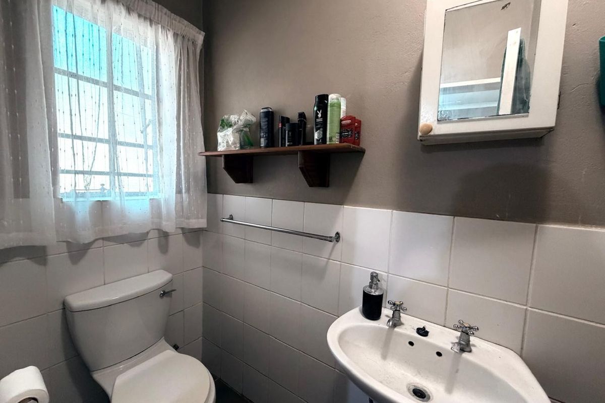A functional bathroom featuring a pedestal basin, toilet, and wall-mounted medicine cabinet with tiled splashback finishes.