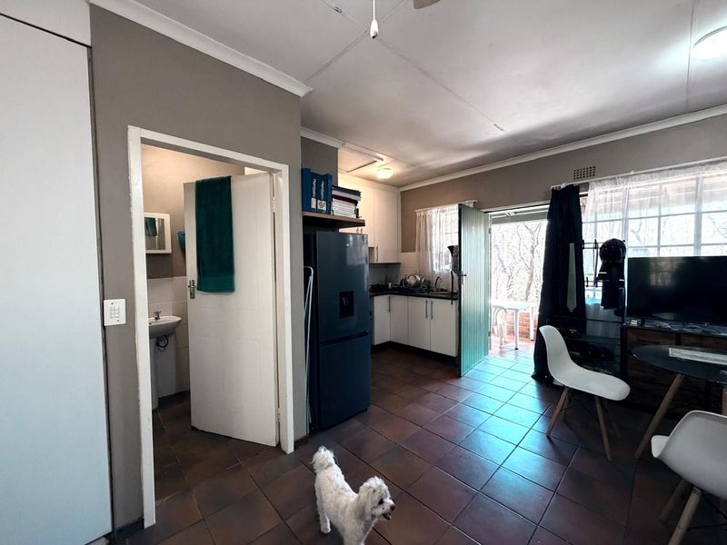Open plan living area featuring tiled flooring, a compact kitchen with built-in cabinetry, and direct access to an adjacent bathroom and outdoor patio area.