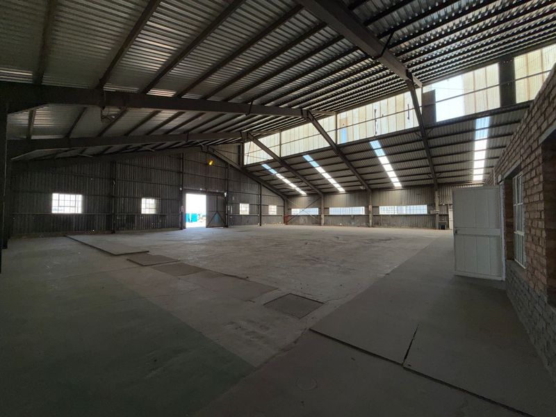Spacious industrial warehouse featuring a high-clearance steel portal frame, concrete flooring, and natural light provided by translucent roof panels.