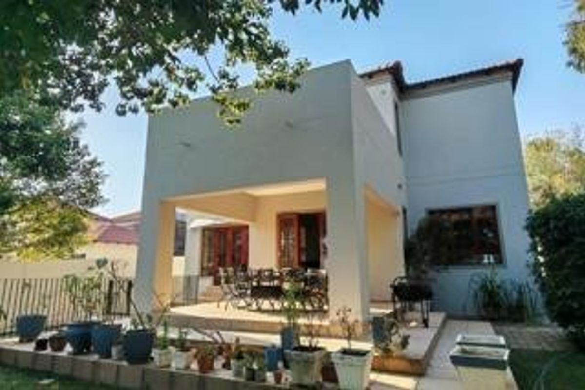 A rear view of the property featuring a covered patio area with tiled flooring and access to the interior through sliding doors.