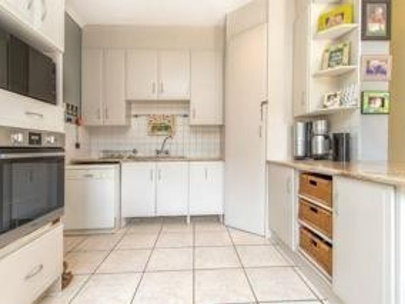 A functional kitchen featuring built-in cabinetry, integrated appliances including an oven and microwave, tiled flooring, and a tiled backsplash.