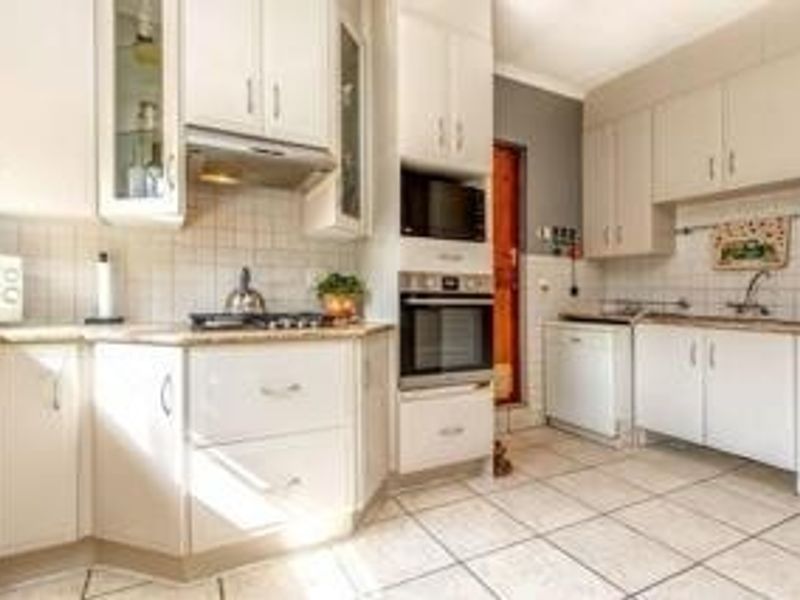 A functional kitchen featuring white cabinetry, built-in oven and microwave, tiled backsplash, and tiled flooring with ample counter space.
