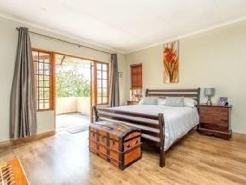 Spacious bedroom featuring laminate flooring and large sliding glass doors that open onto a private balcony, providing ample natural light.