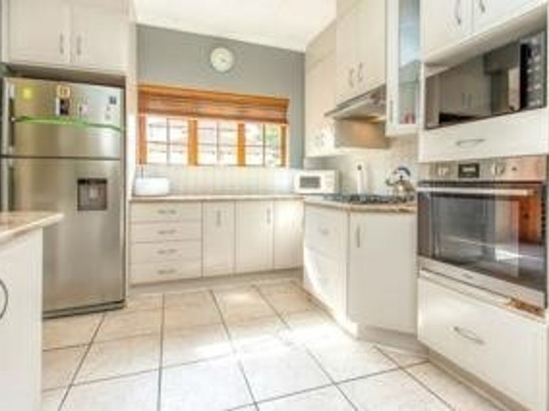 A functional kitchen featuring white cabinetry, tiled flooring, a built-in oven, microwave, and extractor fan, offering a clean and practical workspace.