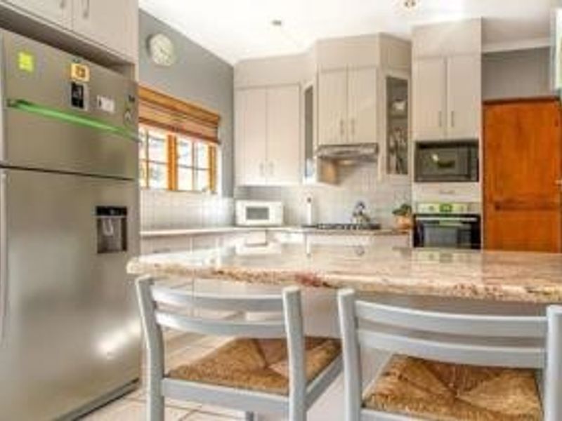 A functional kitchen featuring granite countertops, ample built-in cabinetry, and integrated appliances including an oven, microwave, and extractor fan.
