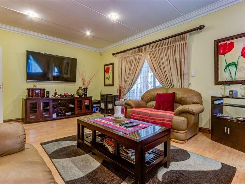 A comfortable living room featuring laminate flooring, recessed downlighting, and decorative cove molding, providing a functional and well-lit space for relaxation.
