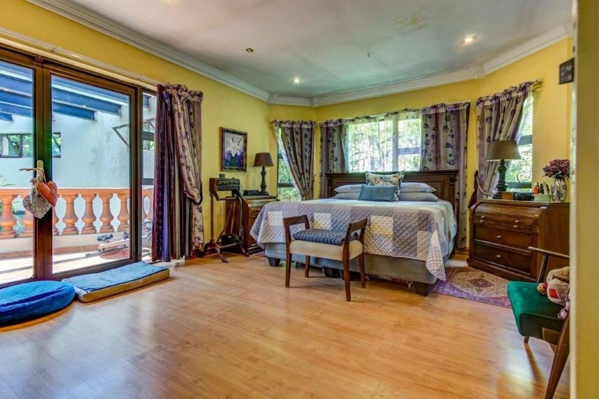 Spacious bedroom featuring laminate flooring, crown molding, recessed lighting, and direct access to an outdoor balcony through sliding glass doors.