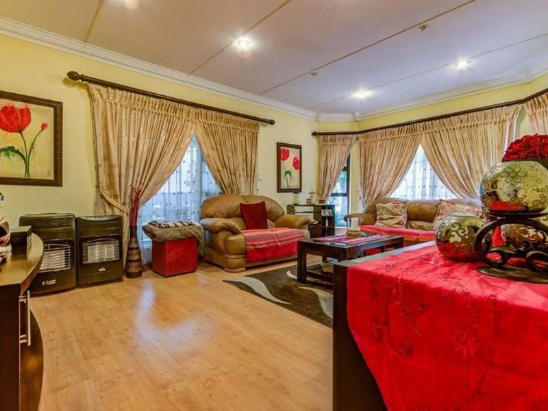 A spacious living room featuring laminate flooring, recessed ceiling lighting, and a bay window, providing a comfortable and well-lit area for relaxation.