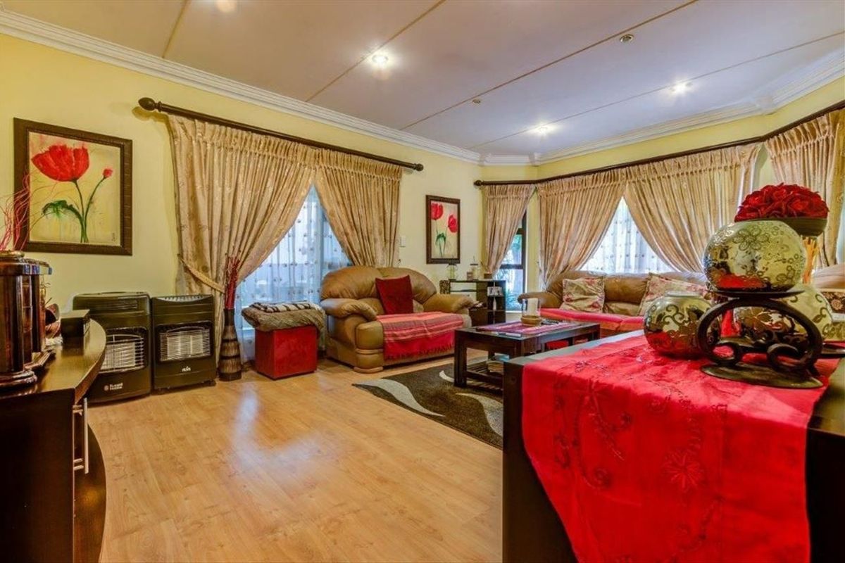 A spacious living room featuring laminate flooring, recessed ceiling lighting, and a bay window, providing a comfortable and well-lit area for relaxation.