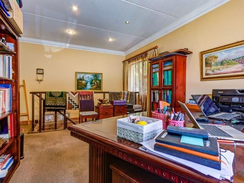 A functional home office space featuring carpeted flooring, recessed lighting, and decorative crown molding, overlooking an adjacent lower level via a staircase railing.
