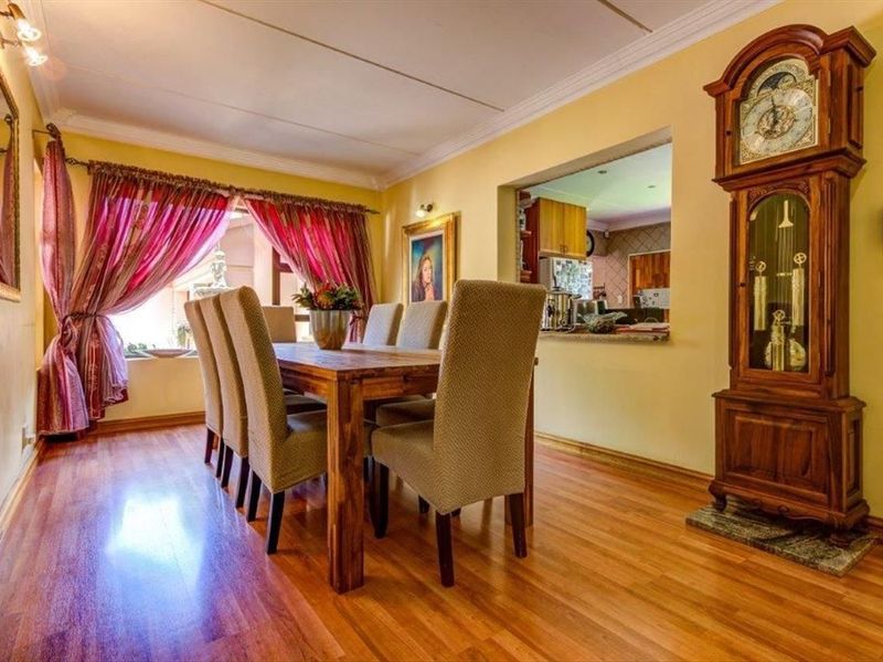 Dining room featuring laminate flooring, coved ceilings, and a convenient pass-through window connecting to the kitchen area.