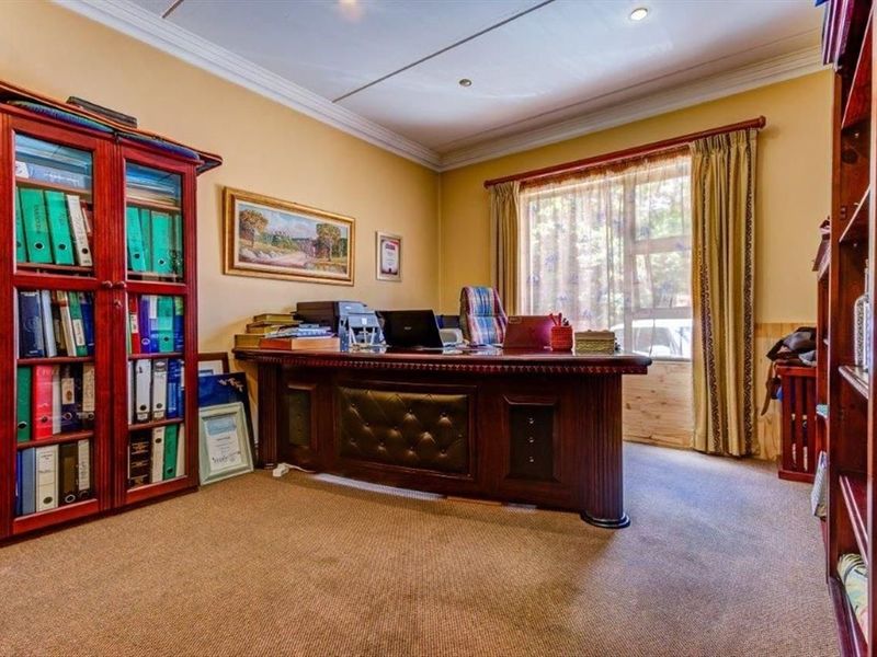A functional home office featuring neutral walls, crown molding, recessed lighting, and a large window providing natural light.